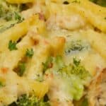 Baked Chicken and Broccoli Alfredo casserole with penne, tender broccoli, juicy chicken, melted cheese, and a garnish of chopped herbs.