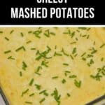 A glass baking dish filled with Cheesy Mashed Potatoes, topped with chopped chives. Text above reads "BAKED CHEESY MASHED POTATOES.