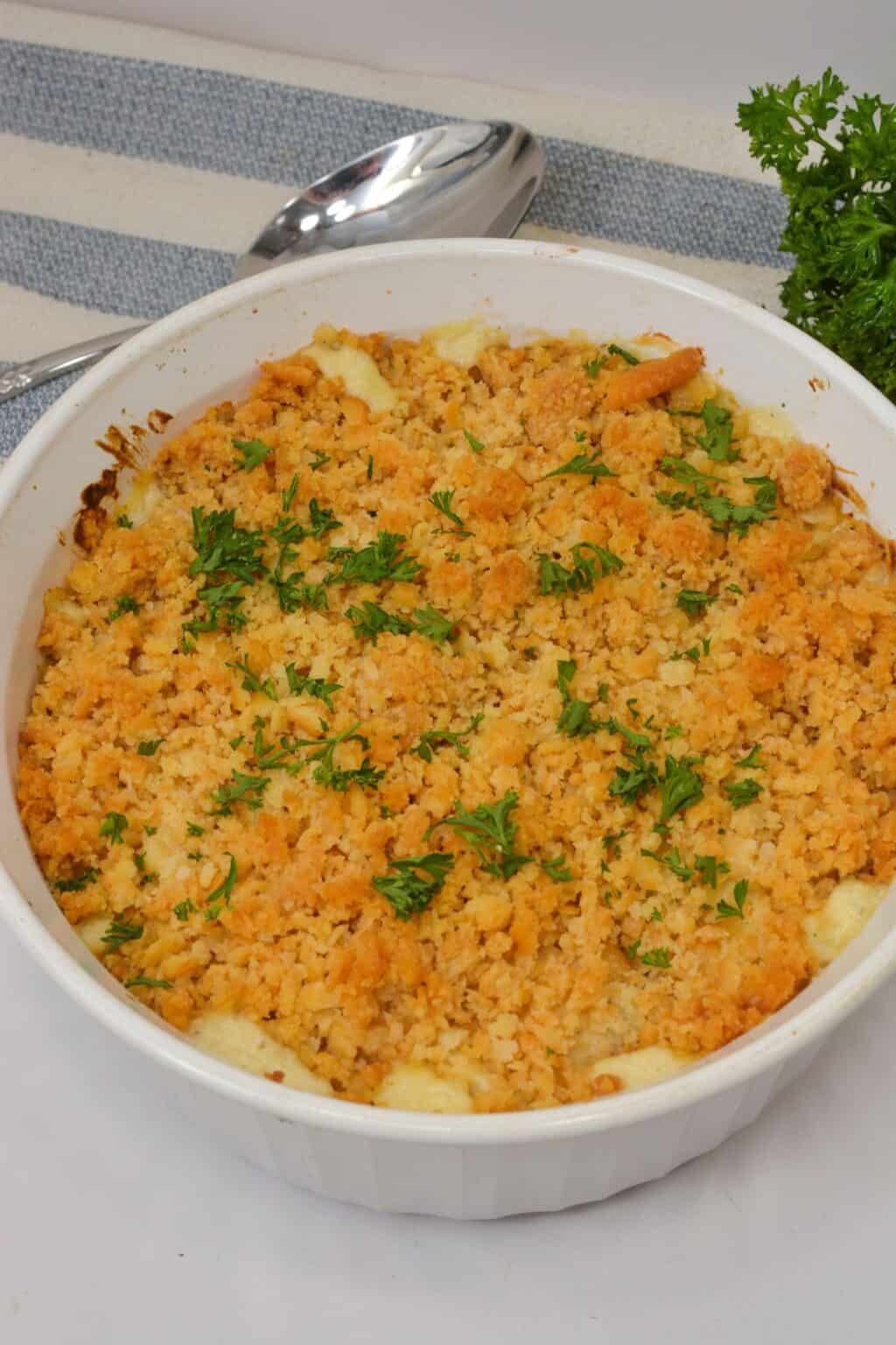 A white casserole dish filled with Ritz Cracker Chicken Casserole, baked to perfection and topped with golden brown breadcrumbs, garnished with chopped parsley.