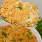 A close-up of a serving with a golden breadcrumb topping and garnished with parsley. The dish is visible in the background.