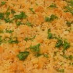 A close-up view of Ritz Cracker Chicken Casserole topped with golden brown breadcrumbs and garnished with fresh parsley in a white dish.
