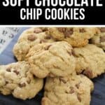 A pile of Soft Chocolate Chip Cookies is displayed on a dark surface, with a sign above labeling them as "Chewy Soft Chocolate Chip Cookies.