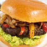 A hamburger with caramelized onions, red peppers, and guacamole on a bun, with text reading "15 Easy Ground Beef Recipes"—perfect for anyone craving delicious and satisfying beef dishes.