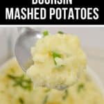 A spoonful of creamy Boursin Mashed Potatoes garnished with chopped chives, with a bowl of fluffy potatoes in the background. Text overlay reads "Creamy Boursin Mashed Potatoes.