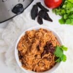 A bowl sits next to a steaming pot filled with even more of the flavorful dish.