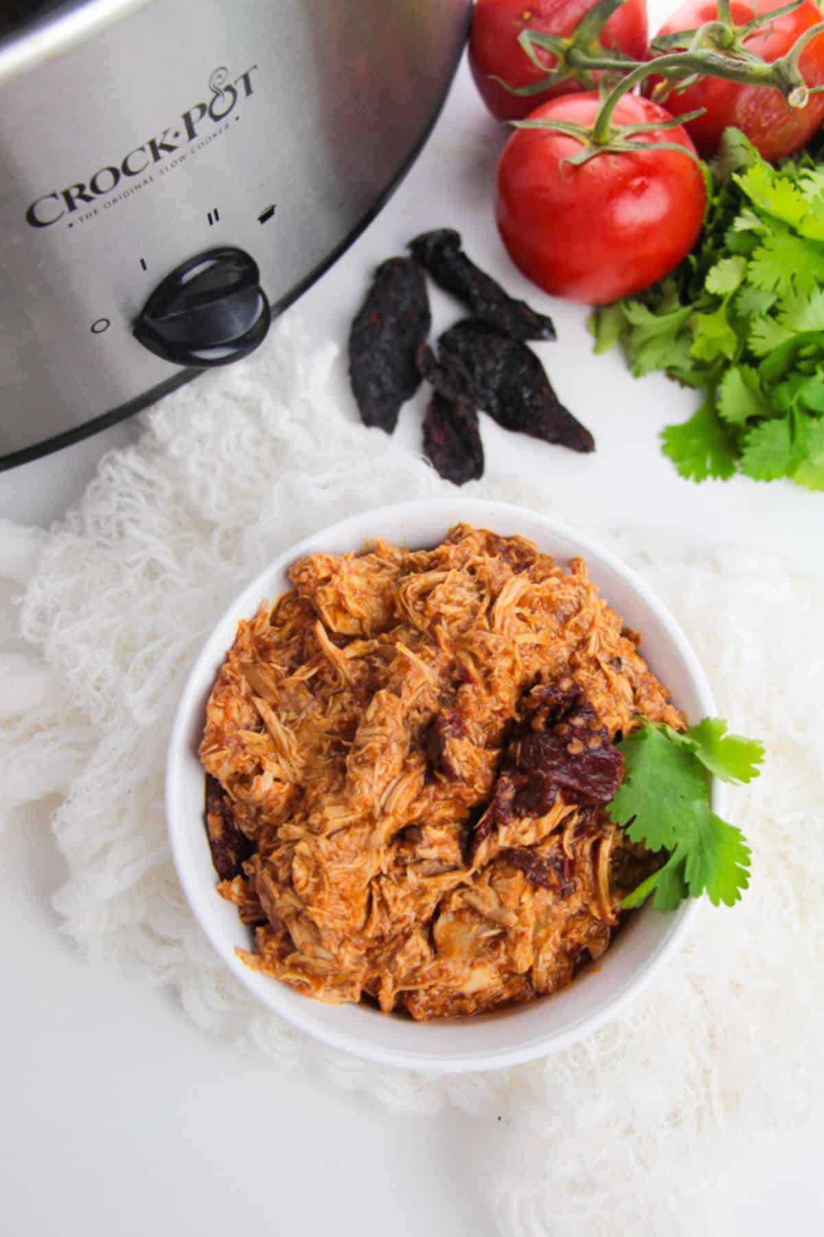 A bowl  sits next to a steaming pot filled with even more of the flavorful dish.