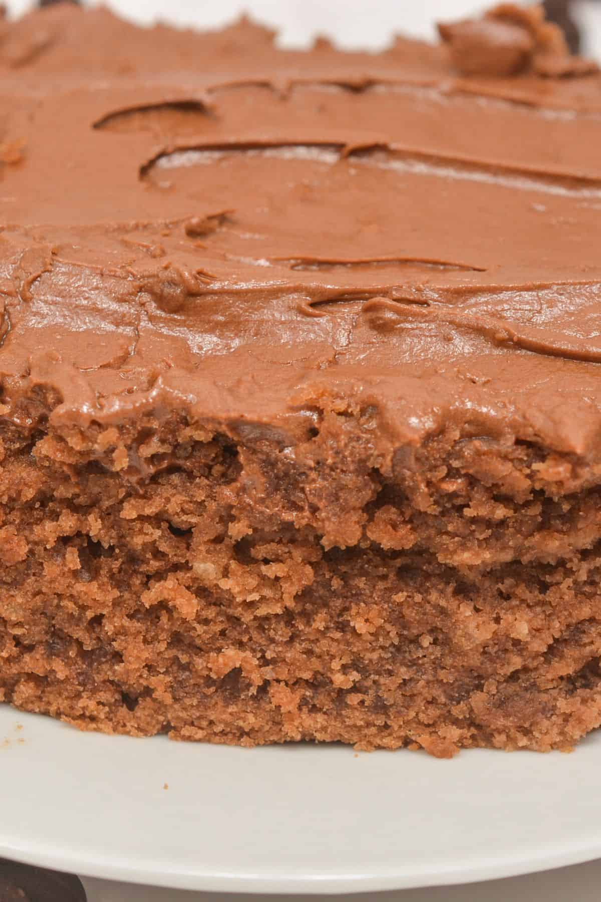 A close-up of a rectangular Cocoa Mayonnaise Cake with rich chocolate frosting, shown on a white plate.