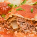 Close-up of Easy Stuffed Cabbage Rolls filled with ground meat, rice, and onions, topped with tomato sauce and garnished with chopped parsley.