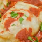 A close-up of Easy Stuffed Cabbage Rolls topped with tomato sauce and garnished with chopped parsley.