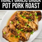 Sliced Crock Pot Pork Roast with honey garlic glaze, garnished with chopped green onions and served on a white oval plate.