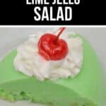 A slice of classic Lime Jello Salad topped with whipped cream and a maraschino cherry, served on a white plate.