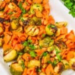 Vegetables garnished with chopped parsley are served on a white parchment-lined tray.