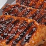 Four grilled pork chops coated in a glossy, dark barbecue sauce are arranged on a white plate, making this the perfect Pork Chop Dinner. Bold text at the bottom reads "Favorite Pork Chop Recipes.