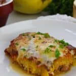 A slice of Spaghetti Squash Lasagna casserole, topped with melted cheese and chopped parsley, served on a white plate.