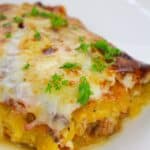 A slice of cheesy Spaghetti Squash Lasagna topped with chopped parsley, served on a white plate.