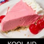 A slice of Kool Aid Pie with a pink filling, a graham cracker crust, whipped cream on top, and maraschino cherries on the side.