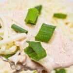 A close-up of a creamy dip topped with shredded cheese and chopped green onions, reminiscent of the rich flavors found in a classic Salsa and Cream Cheese Dip.