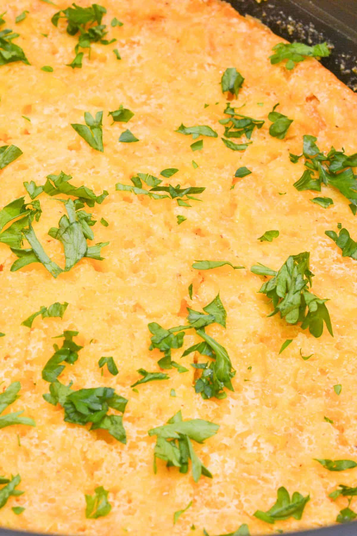 Close-up of a baked dish topped with gooey cheese and chopped fresh parsley.