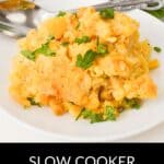 A serving of Slow Cooker Corn Casserole garnished with chopped parsley on a white plate, with a spoon and fresh herbs in the background.
