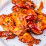 A white plate with the appetizer glazed to perfection and garnished with chopped herbs, set on a light-colored surface.