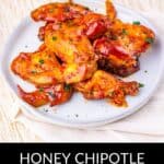 Plate of honey chipotle glazed Slow Cooker Chicken Wings garnished with herbs, arranged on a white plate atop a textured cloth. Text below reads: "Honey Chipotle Slow Cooker Chicken Wings.