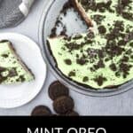 A glass pie dish with decadent Oreo Pudding Pie topped with crushed Oreos, one creamy slice served on a white plate, and whole Oreos on the side.