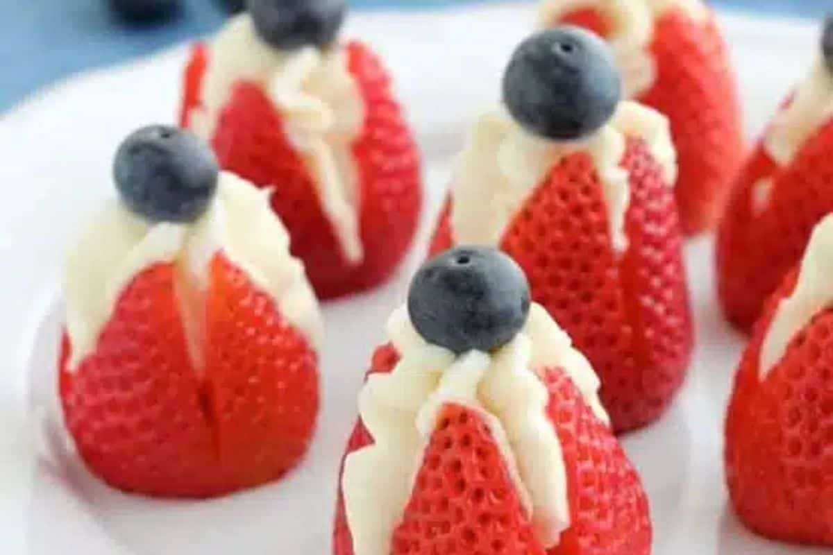 Strawberries with a cream filling, topped with blueberries and arranged on a white plate—one of the prettiest desserts and perfect for spring recipes.