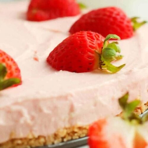 A close-up of a strawberry cheesecake with a crumbly crust, topped with halved fresh strawberries—one of the prettiest spring desserts that's perfect for any Spring Dessert Recipes collection.