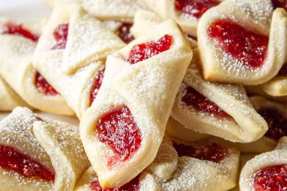 A close-up of several pretty desserts filled with red jam and sprinkled with powdered sugar—perfect inspiration for spring recipes.