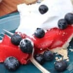 A slice of red gelatin dessert topped with whipped cream and fresh blueberries sits on a blue plate with a fork. Text reads: "The Easiest Summer Desserts." Perfect for anyone craving the easiest desserts to enjoy all season long.