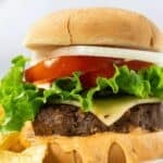 Close-up of a cheeseburger with lettuce, tomato, onion, and sauce on a bun. Text reads: “12 Must Try Burgers That Bring Big Flavor.”.