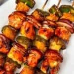 Three skewers on a white plate.