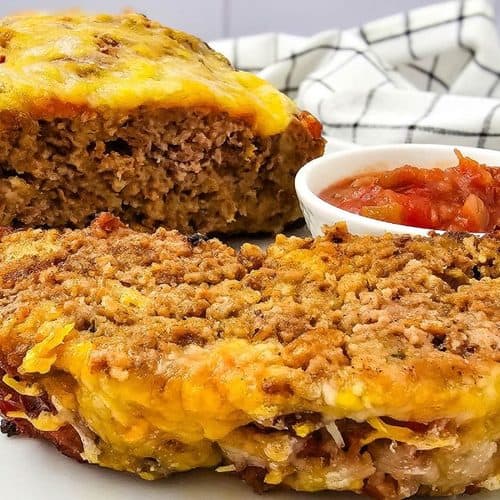 Two slices of salsa meatloaf topped with melted cheese, served with a small bowl of salsa.